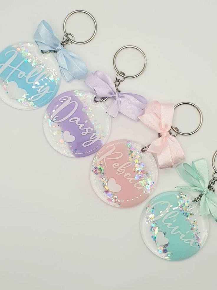 four keychains with different designs and colors on them, one has a bow