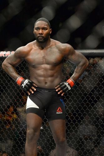 a man standing in front of a fence with his hands on his hips and wearing boxing gloves