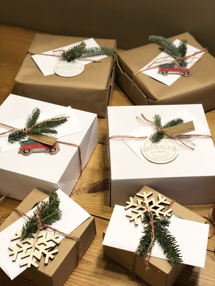 four boxes are wrapped in brown paper and decorated with snowflakes, pine cones, and twine