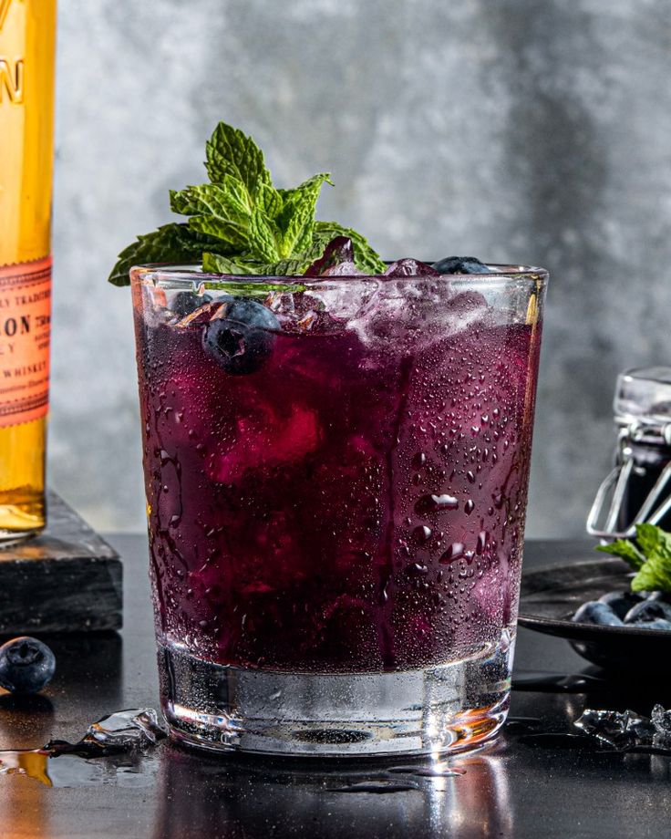 a close up of a drink in a glass on a table next to a bottle