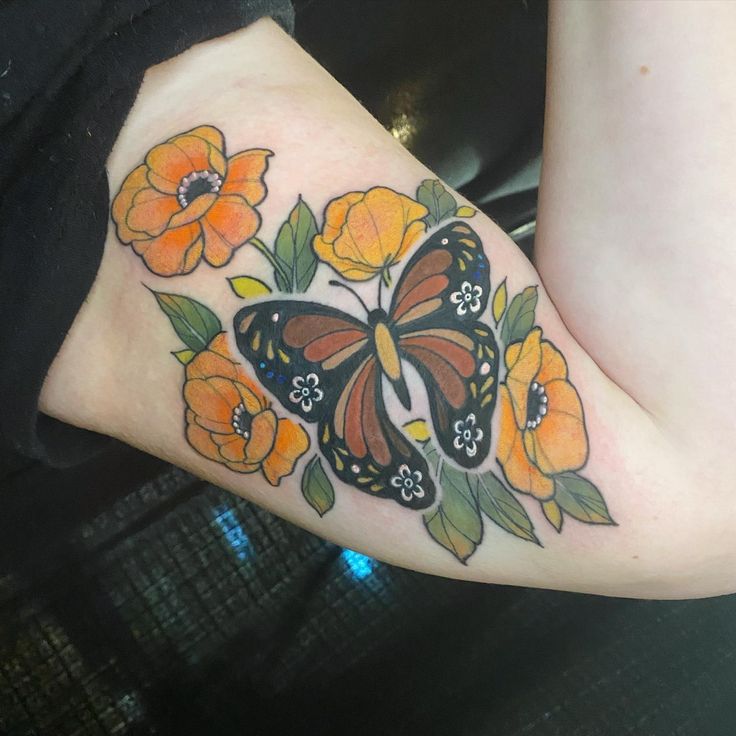 a butterfly and flowers tattoo on the left side of the leg, which is decorated with orange flowers