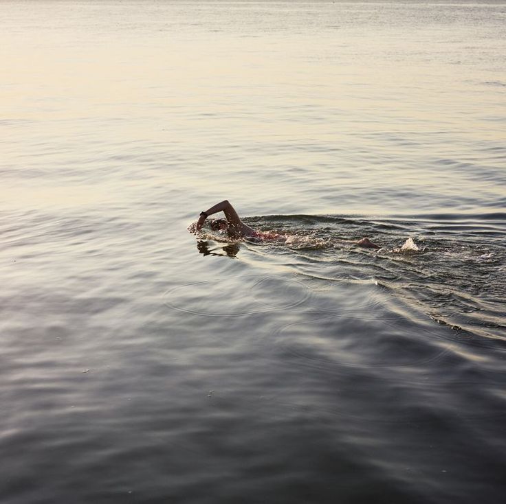 a person swimming in the water with their head above the water's surface,