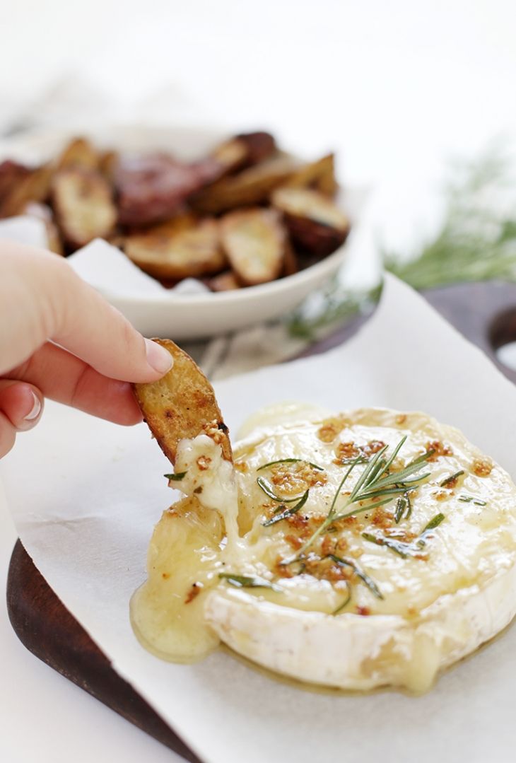 a person dipping something into a bowl with some food in the background on a napkin