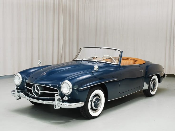 an old blue mercedes sports car parked in a garage