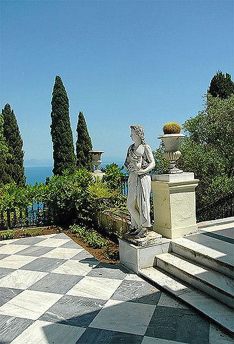 a statue is sitting on top of a checkerboard floor in front of some trees