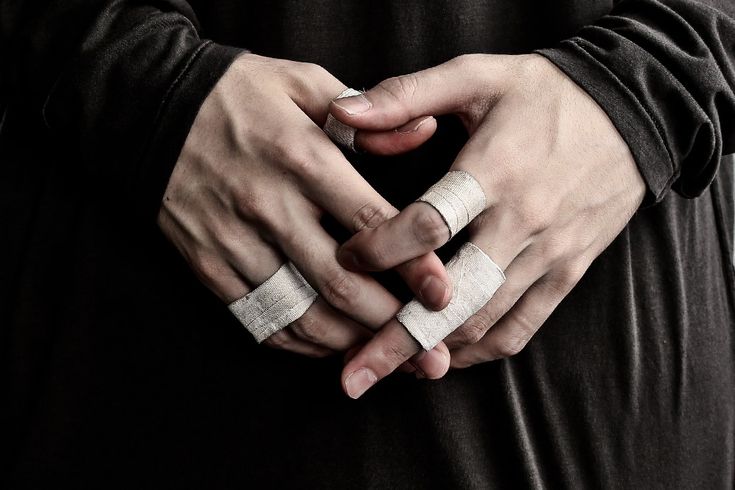 two hands holding onto each other with bandages on their fingers and one hand in the shape of a heart