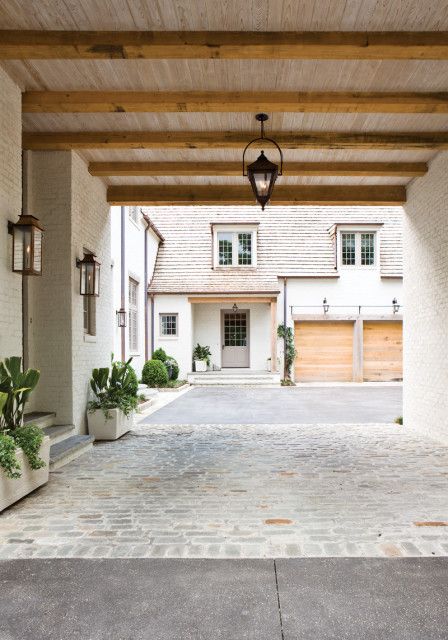 an empty driveway with potted plants on either side