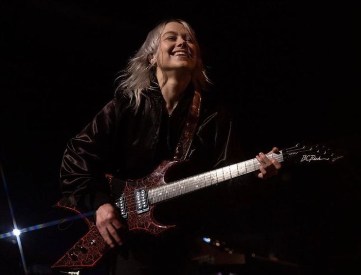 a man playing an electric guitar in the dark