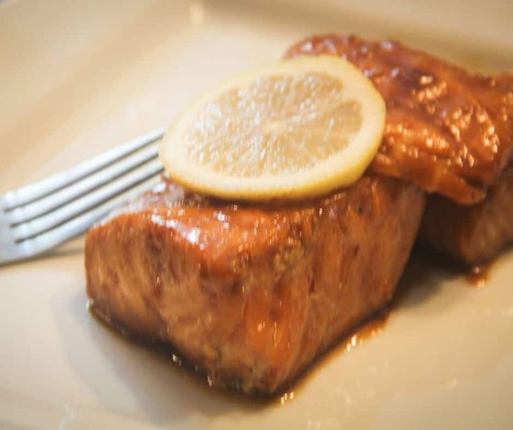 a white plate topped with meat covered in gravy and a slice of lemon