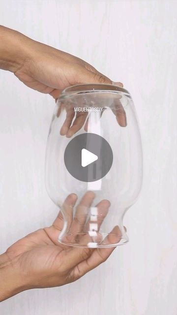 two hands are holding a clear glass bowl