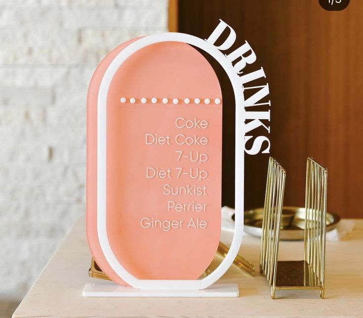 a pink sign sitting on top of a table next to a gold plated object