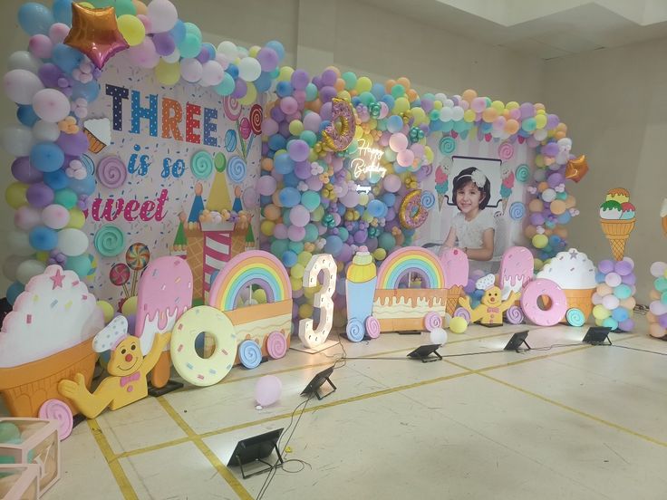 an ice cream themed birthday party with balloons and streamers on the wall behind it