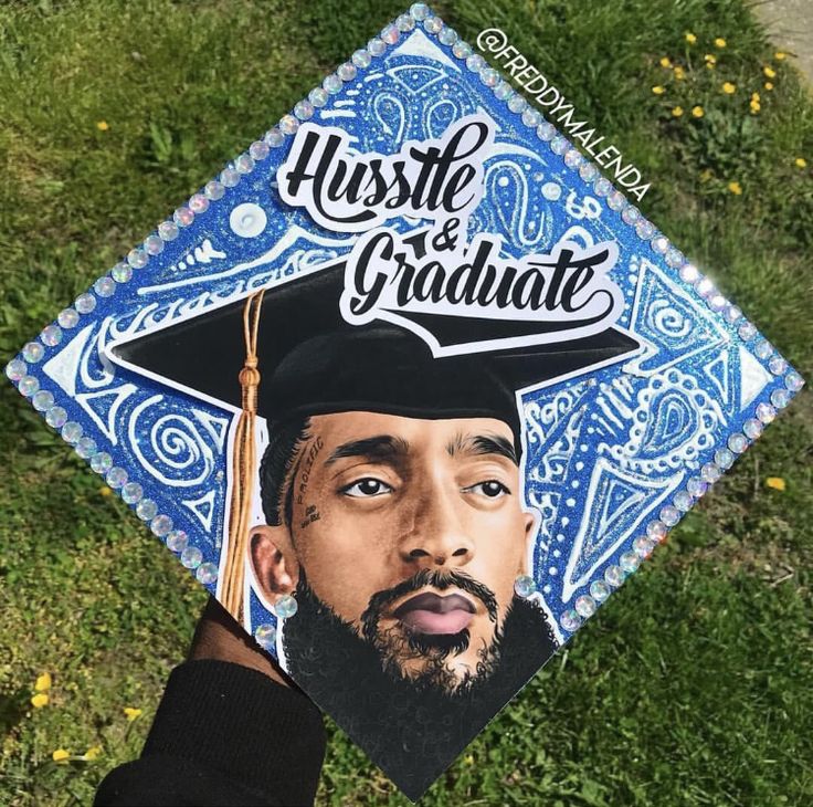 a hand holding up a graduation cap with the image of a man wearing a hat