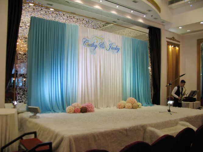 a stage set up for an event with blue drapes and flowers on the table