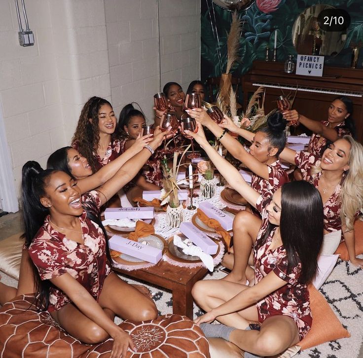 a group of women sitting around a table holding wine glasses