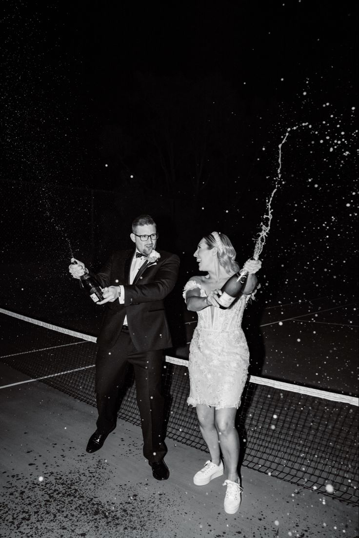 a man and woman standing next to each other on a tennis court with confetti in their hands