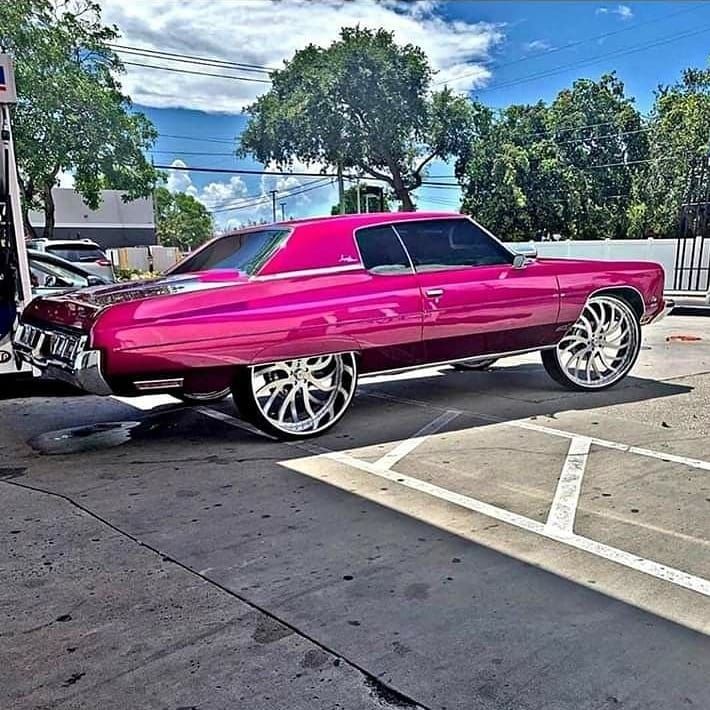 a pink car parked in a parking lot