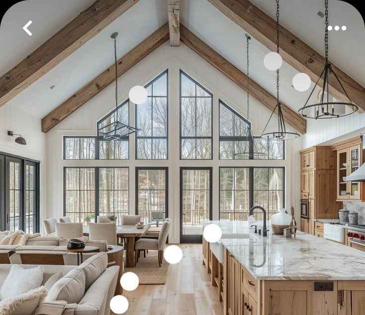 a large open concept kitchen and living room in a house with high ceilings, wood flooring and white walls