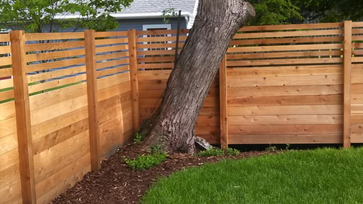 a wooden fence next to a tree in a yard