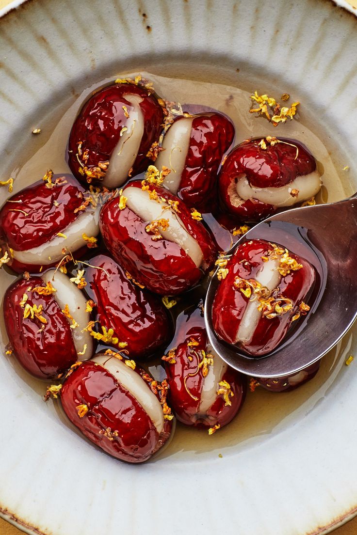 a white bowl filled with lots of food on top of a yellow table next to a spoon