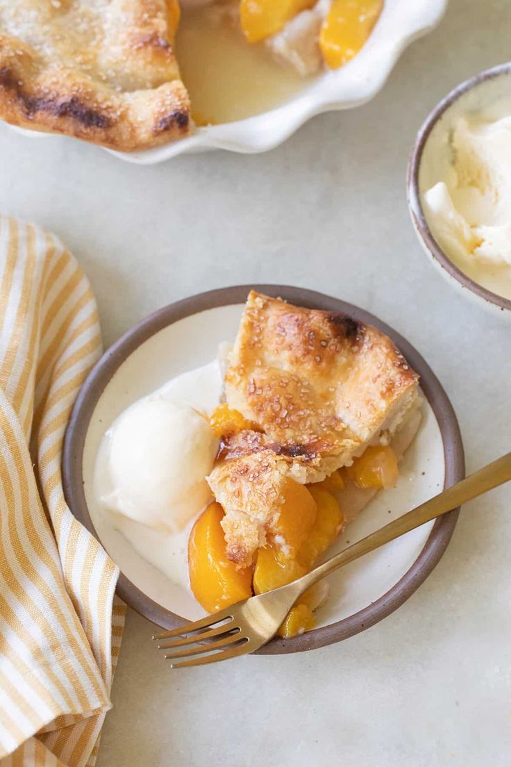 a slice of peach cobbler on a plate with ice cream and a fork next to it