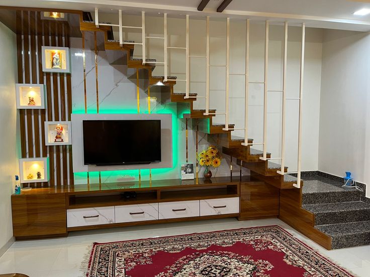 a living room with stairs and a television on top of the entertainment center that is built into the wall