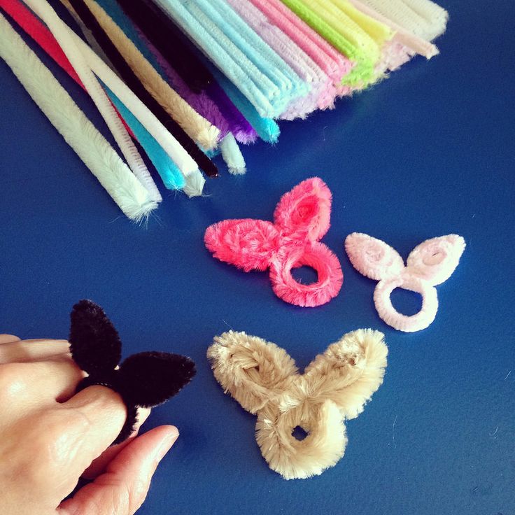 a person is holding several small animal hair clips in front of some other items on a blue surface