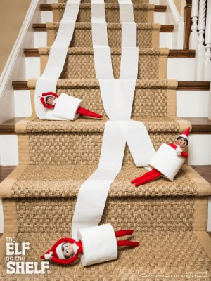 two elfs are on the stairs with toilet paper