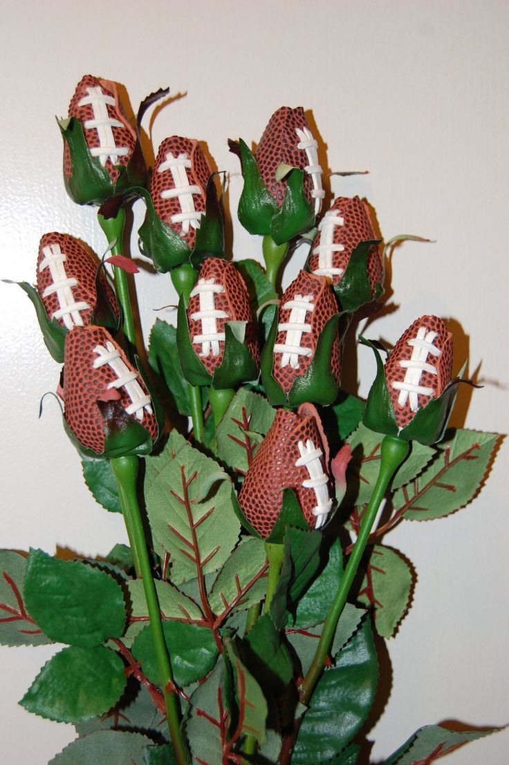 a vase filled with red flowers covered in white footballs on top of green leaves