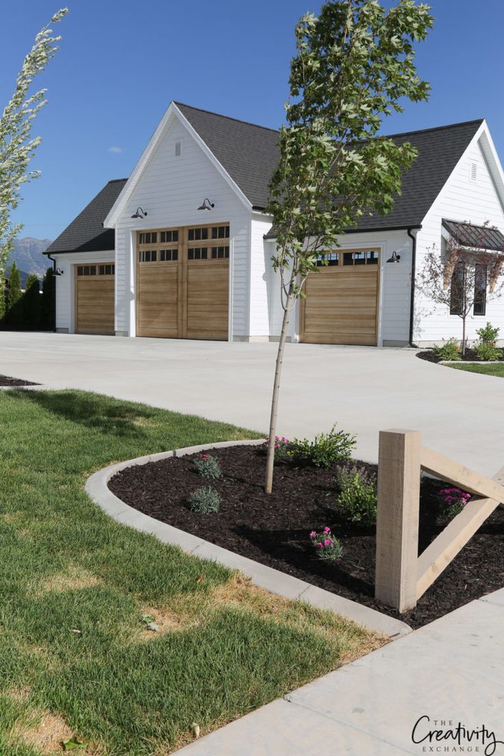 a house with two garages and a tree in the front yard