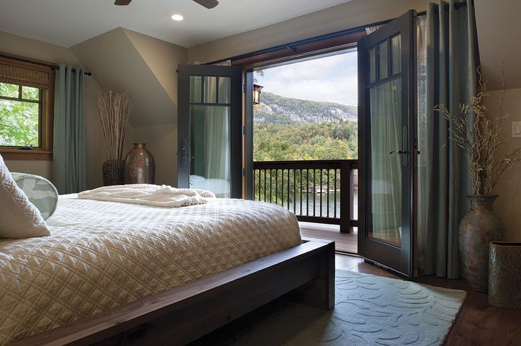 a bedroom with a large bed and sliding glass doors leading to a balcony overlooking the mountains