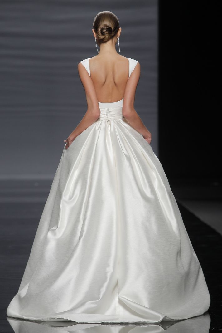 a woman in a white wedding dress walking down the runway with her back to the camera