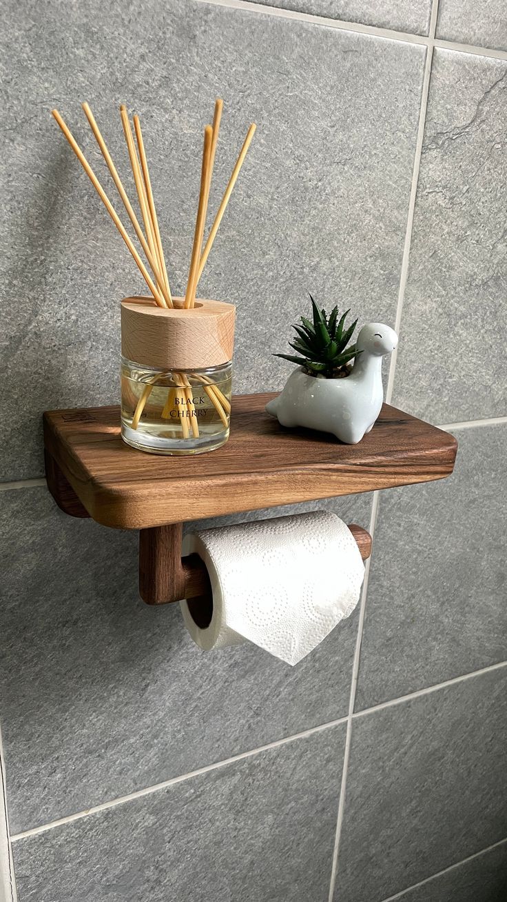 a wooden shelf holding a glass jar with reeds and a potted plant on it