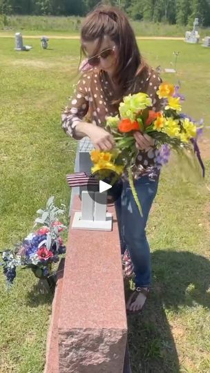 a woman placing flowers on a memorial