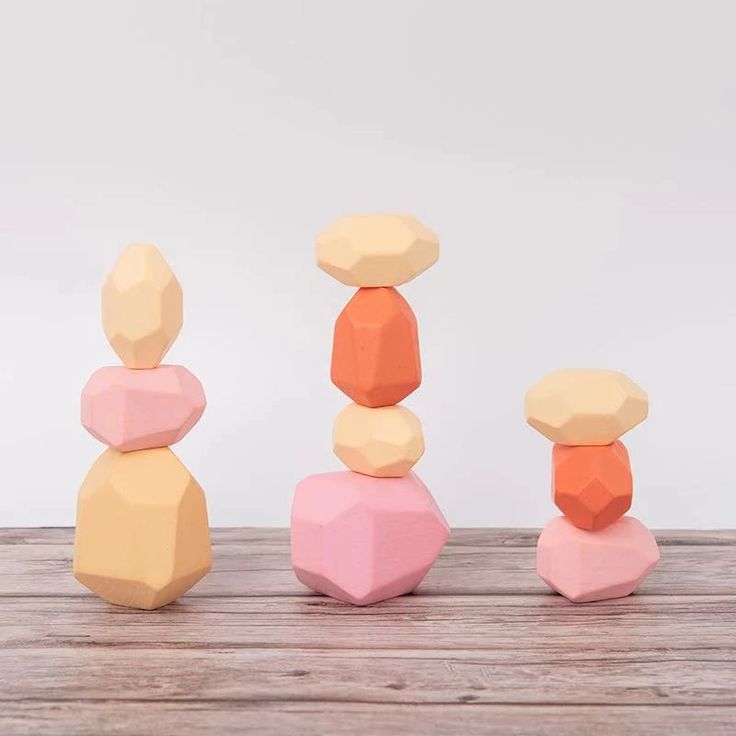 three colorful rocks stacked on top of each other in front of a white wall and wooden floor