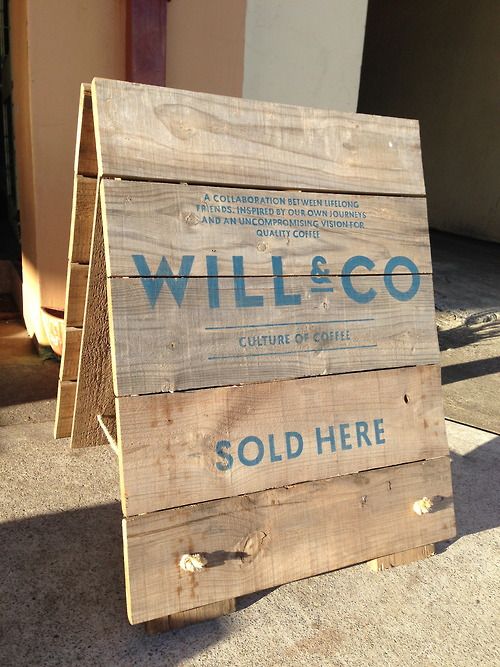 a wooden sign sitting on top of a sidewalk