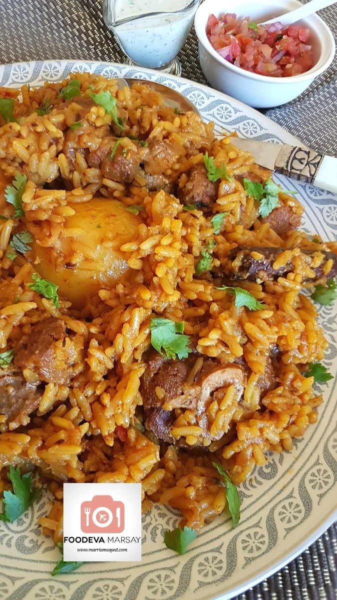 a plate full of rice and meat with garnishes on the table top