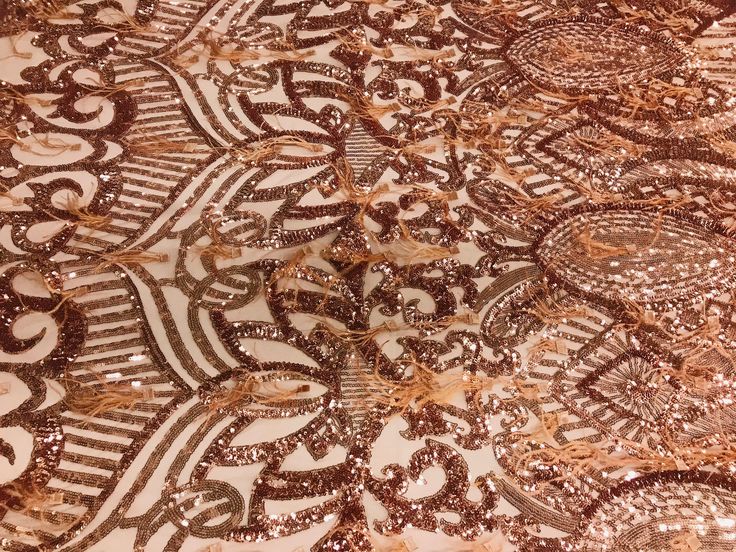 an intricately designed table cloth with gold sequins and brown lace on it