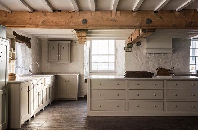 an old fashioned kitchen with white cabinets and wood beams on the ceiling is pictured in this image