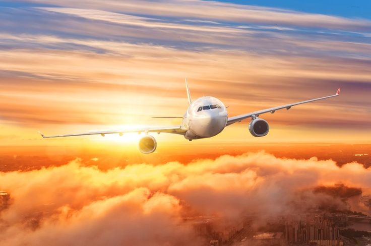 an airplane flying above the clouds at sunset