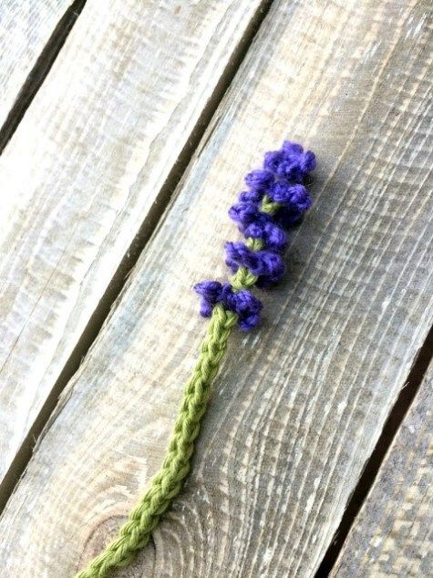 a crocheted purple flower sitting on top of a wooden table