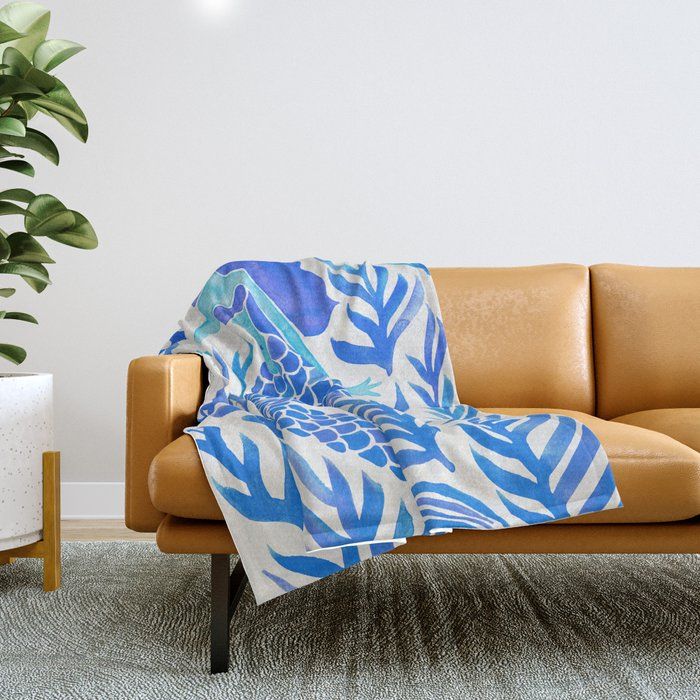 a couch with a blanket on it next to a potted plant