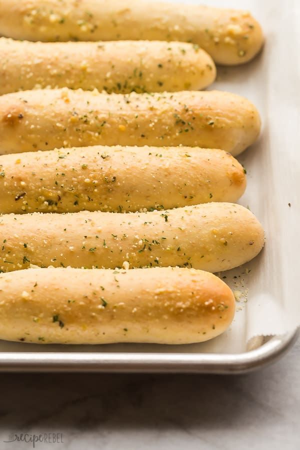 breadsticks in a baking pan with seasoning on them