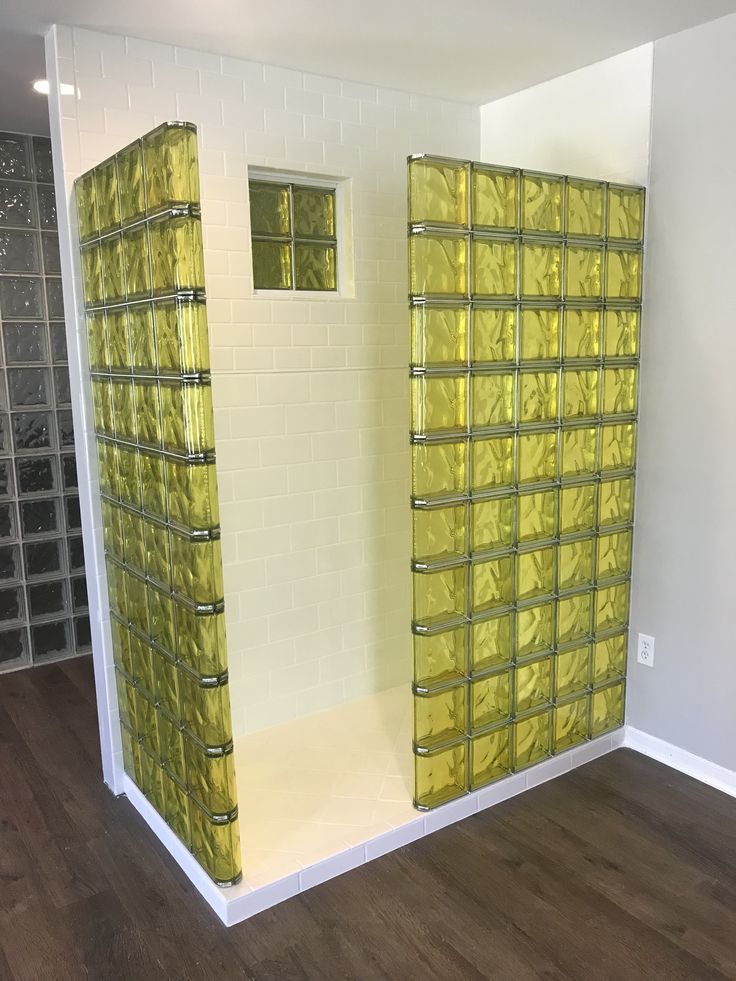 an empty room with yellow glass blocks on the wall and wood flooring in front of it