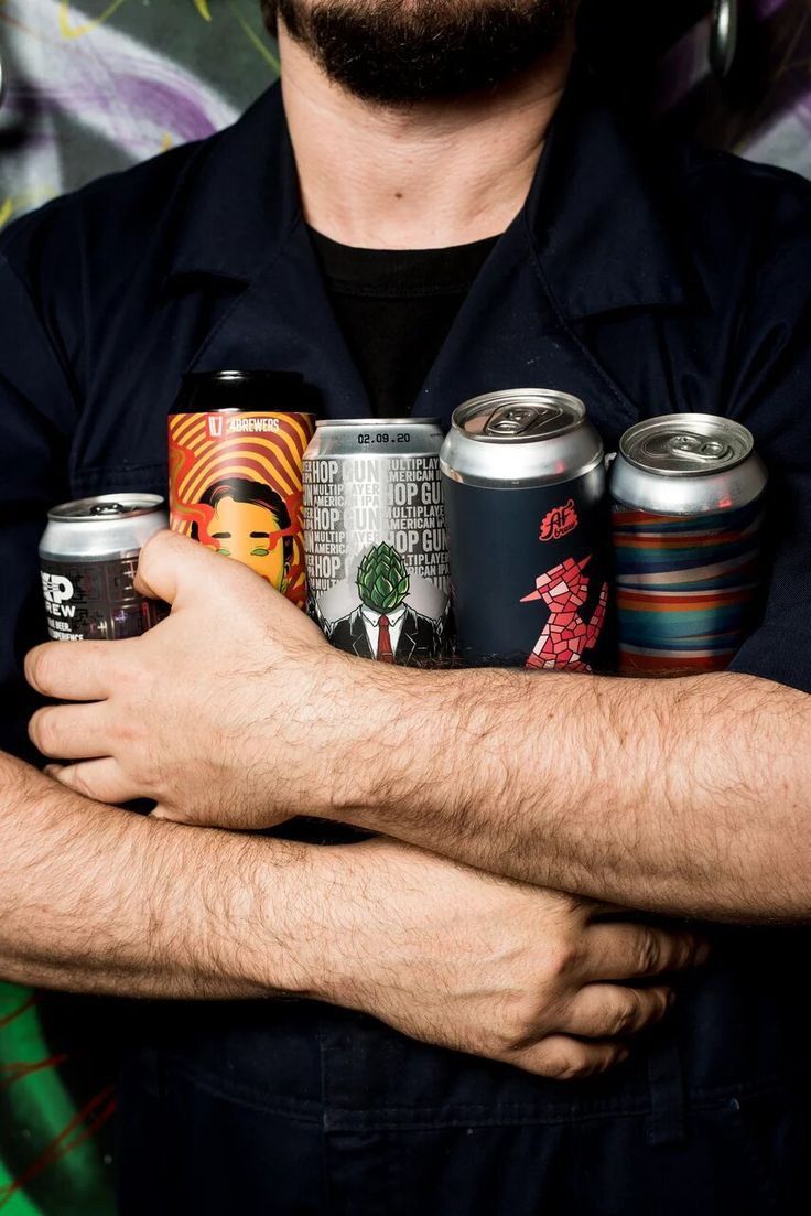 a man with his arms crossed holding six cans of beer