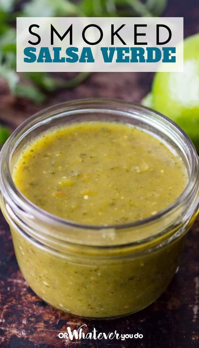 a glass jar filled with salsa sitting on top of a table next to an apple