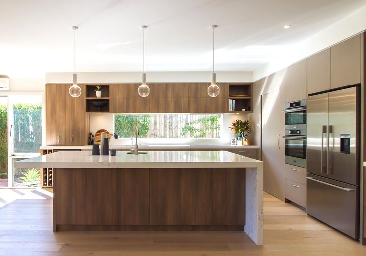 a large kitchen with an island in the middle and lots of lights hanging from the ceiling