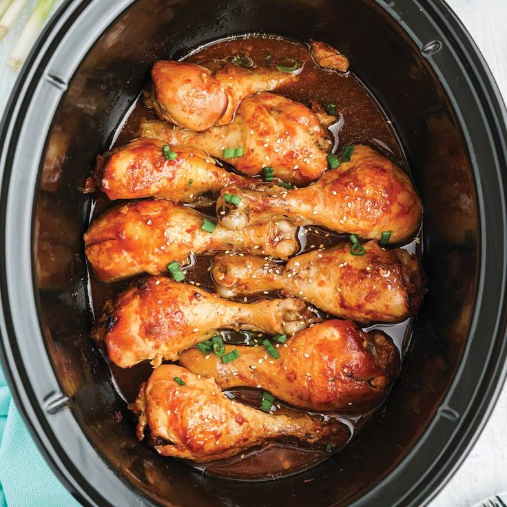 chicken legs in a slow cooker with brown sauce and parsley on the side