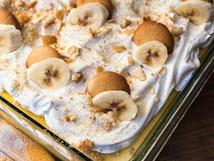 a dessert with bananas and cream in a glass dish on top of a wooden table