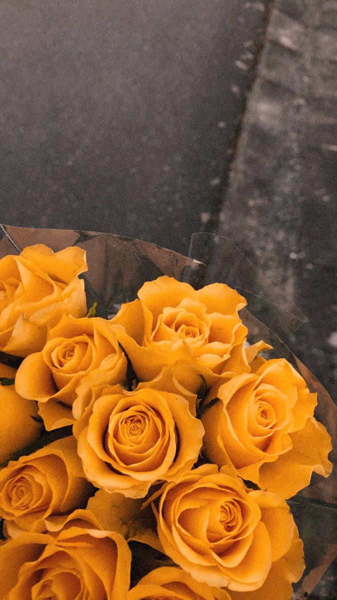 a bouquet of yellow roses sitting on the side of a road next to a street